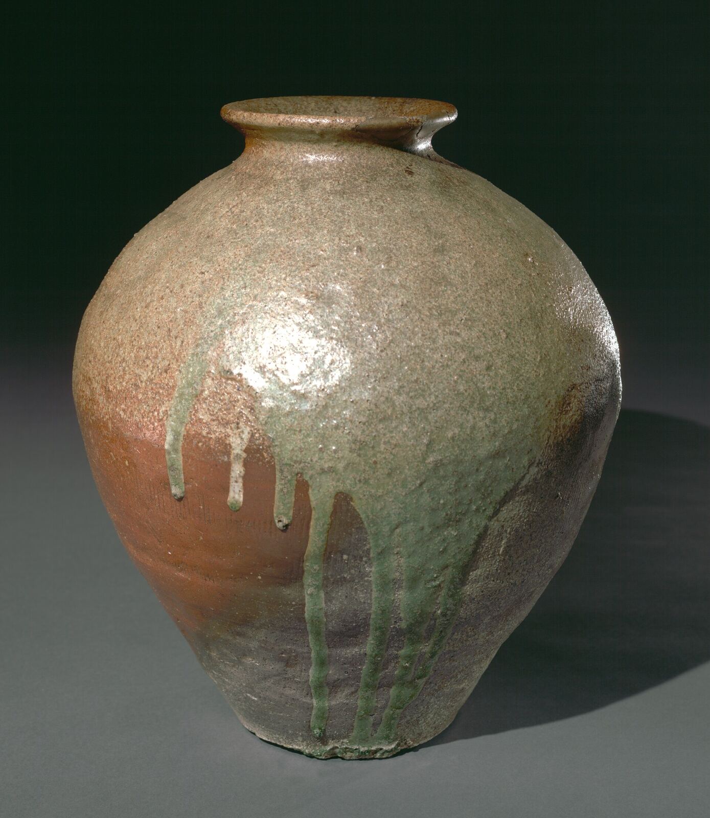 A Tamba ware storage jar from the Muromachi period, its green ash glaze running down the shoulder.